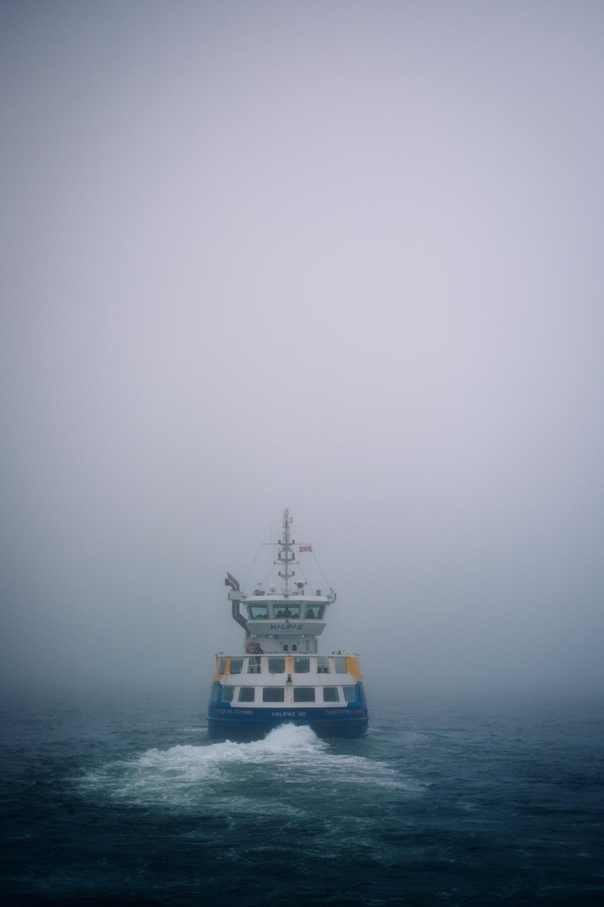 Halifax ferry travelling through dense fog on Halifax Harbour, leaving a wake behind it on the water.