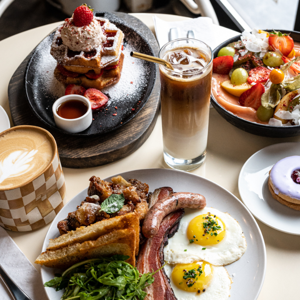 Brunch spread with waffles, eggs, bacon, iced coffee, and fresh fruit in Halifax café